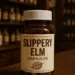 Slippery elm supplement bottle with capsules on a wooden counter inside a vintage apothecary pharmacy, symbolizing traditional herbal medicine and natural digestive health remedies.